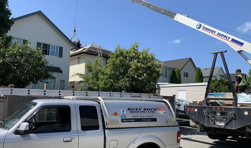 Busy Boys Roofing LTD company truck with residential home roof being repaired in background