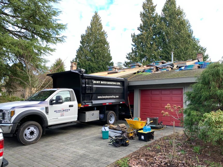 Busy Boys Roofing LTD company truck with the residential home roof being repaired in background