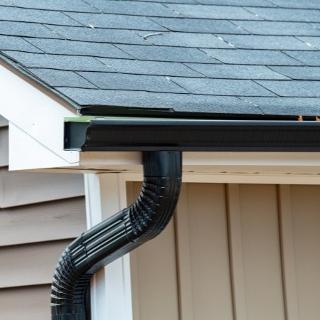 Black gutter installed on a residential home with gray asphalt shingles
